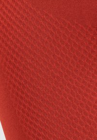 Tessuto rosso testurizzato con un motivo a diamante. Materiale liscio ed elasticizzato, con sezioni a coste sottili a contrasto.