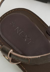 Sandale en cuir marron avec bride réglable indiquant la taille 6,5/40 et logo « NEXT » embossé sur la semelle.