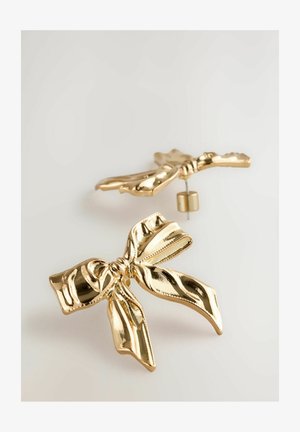 Ohrringe in Goldfarbe, die wie Schleifenbänder geformt sind, mit einer glänzenden Oberfläche und strukturierten Details in der Mitte und an den Rändern.