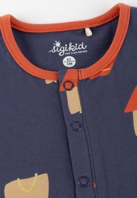 Navy blue long-sleeve onesie featuring orange trim, snap buttons, and colorful patterns of bags and shapes. Textured cotton fabric.