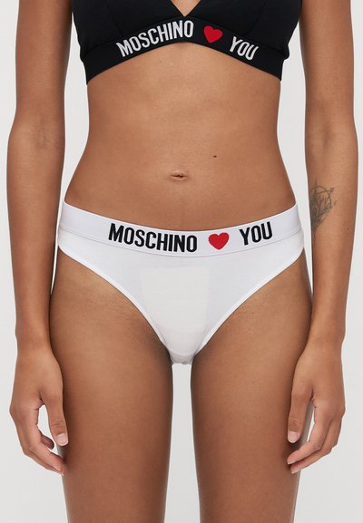 Bijela pamučna tanga gaćice sa širokim crno-bijelim pojasom na kojem je ispisano "MOSCHINO ❤️ YOU". Minimalistički dizajn s glatkom teksturom.