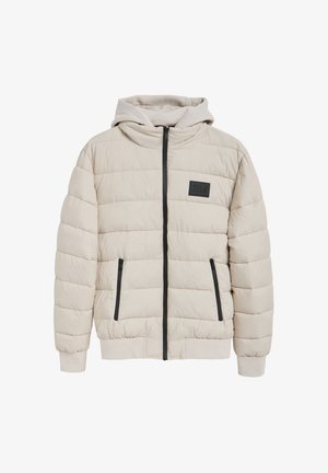 Chaqueta acolchada beige con cremallera frontal, capucha fija, detalles en negro en las cremalleras y una etiqueta tipo parche. Presenta textura acolchada y puños elásticos.