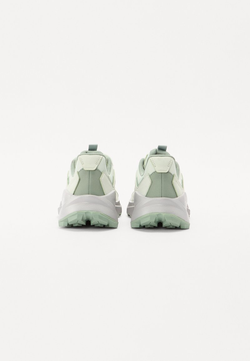 Zapatillas de senderismo en verde y gris con una superficie texturizada, collar acolchado y un patrón de suela resistente para tracción. Cuenta con una lengüeta de agarre.