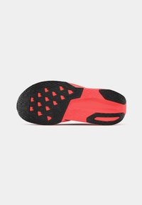 Semelle de chaussure en caoutchouc noir texturé avec des accents rouge vif. Le design comprend des motifs géométriques et des découpes pour une meilleure adhérence.