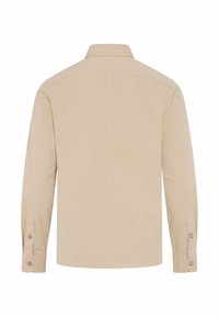 Beige Langarmhemd mit geknöpften Manschetten und Kragen, von hinten auf weißem Hintergrund gezeigt.