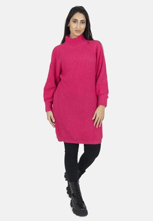 Vestido de punto rosa con cuello alto, textura acanalada y mangas de gran tamaño, combinado con leggings negros y botas negras gruesas.