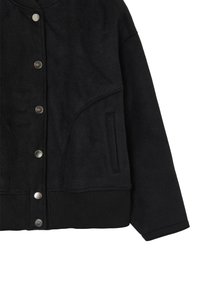 Veste noire en tissu doux, dotée de boutons-pression, d'un col côtelé et d'une poche latérale. Conçue avec une coupe décontractée et oversize.
