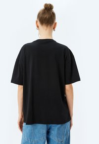 Zwarte katoenen t-shirt met korte mouwen, ontspannen pasvorm en een klassieke ronde hals. Heeft een gladde textuur en een eenvoudig ontwerp.