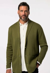 Olivgrüner Strickcardigan mit einem Schalkragen, zwei Fronttaschen und Knöpfen aus einem strukturierten Stoff. Über einem weißen Hemd getragen.