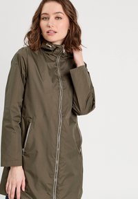 Veste imperméable vert olive avec un col haut, une fermeture éclair frontale complète et des poches latérales avec des accents en matériel argenté.