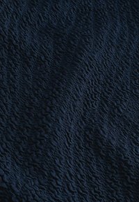 Marineblauer Stoff mit einer strukturierten, wellenförmigen und gekräuselten Oberflächenstruktur, die einen dreidimensionalen Effekt erzeugt.