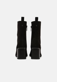 Czarne zamszowe botki za kostkę na kwadratowym obcasie, z zapięciem na zamek błyskawiczny i pętelką z tyłu. Gładka tekstura i minimalistyczny design.