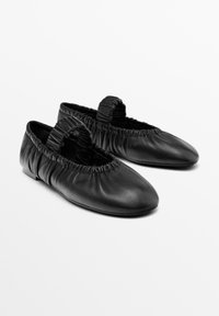 Schwarze Ballerinas aus Leder mit gerafftem Gummizug am Rand, runden Zehen und minimalistischen flachen Sohlen. Keine Verzierungen.