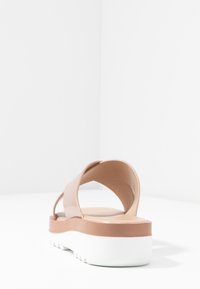 Taupe plattform sandal med breda, böjda remmar och vit gummisula. Slätt material med en ren design, utan synliga mönster eller hårdvara.