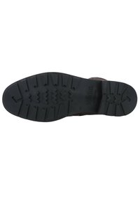 Schwarze Gummisohle mit tiefen Profilrillen und Zickzackmustern; gekennzeichnet mit "solidus". Verfügt über ein robustes und strukturiertes Design für besseren Halt.