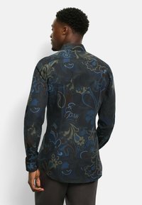 Langärmliges Hemd mit einem dunklen Blumenmuster in Blau und Grün auf schwarzem Hintergrund, mit einem klassischen Kragen und knöpfbaren Manschetten.