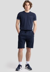 T-shirt en coton bleu marine avec des manches rayées contrastées, associé à un short bleu marine assorti, doté de poches latérales et d'une taille à cordon de serrage.