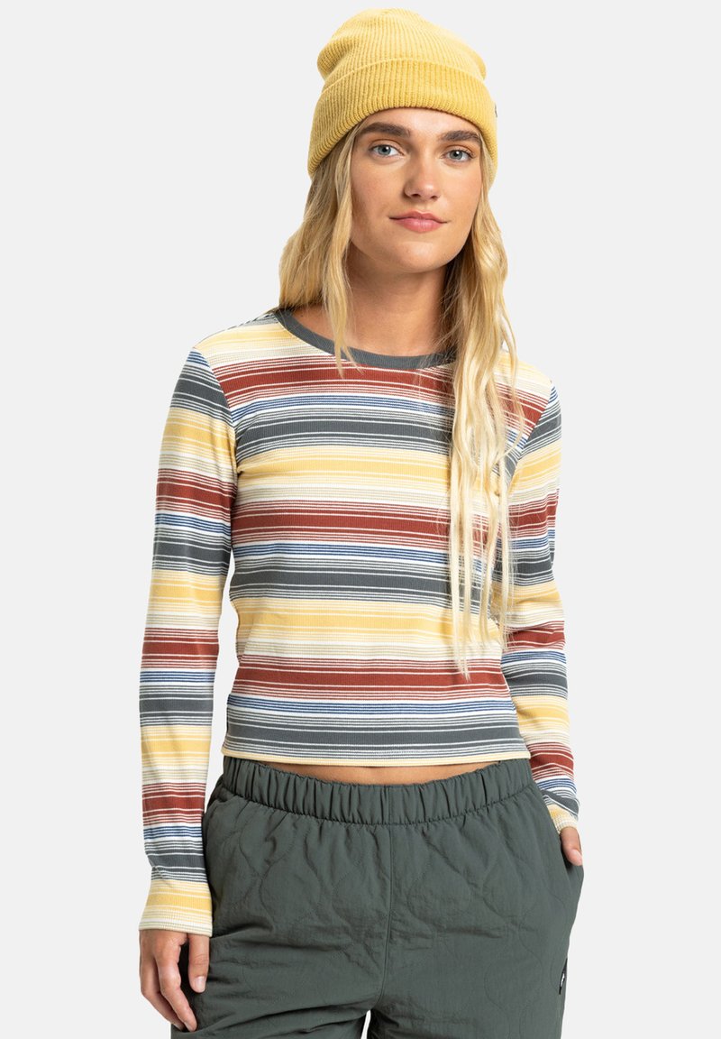 Langschildig geribd shirt met veelkleurige horizontale strepen in geel, blauw, grijs en roest. Gecombineerd met groene elastische tailleband broeken.