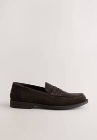 Mocassin homme en daim marron foncé avec petit talon et coutures sur le bout mocassin sur fond neutre, vue de côté.