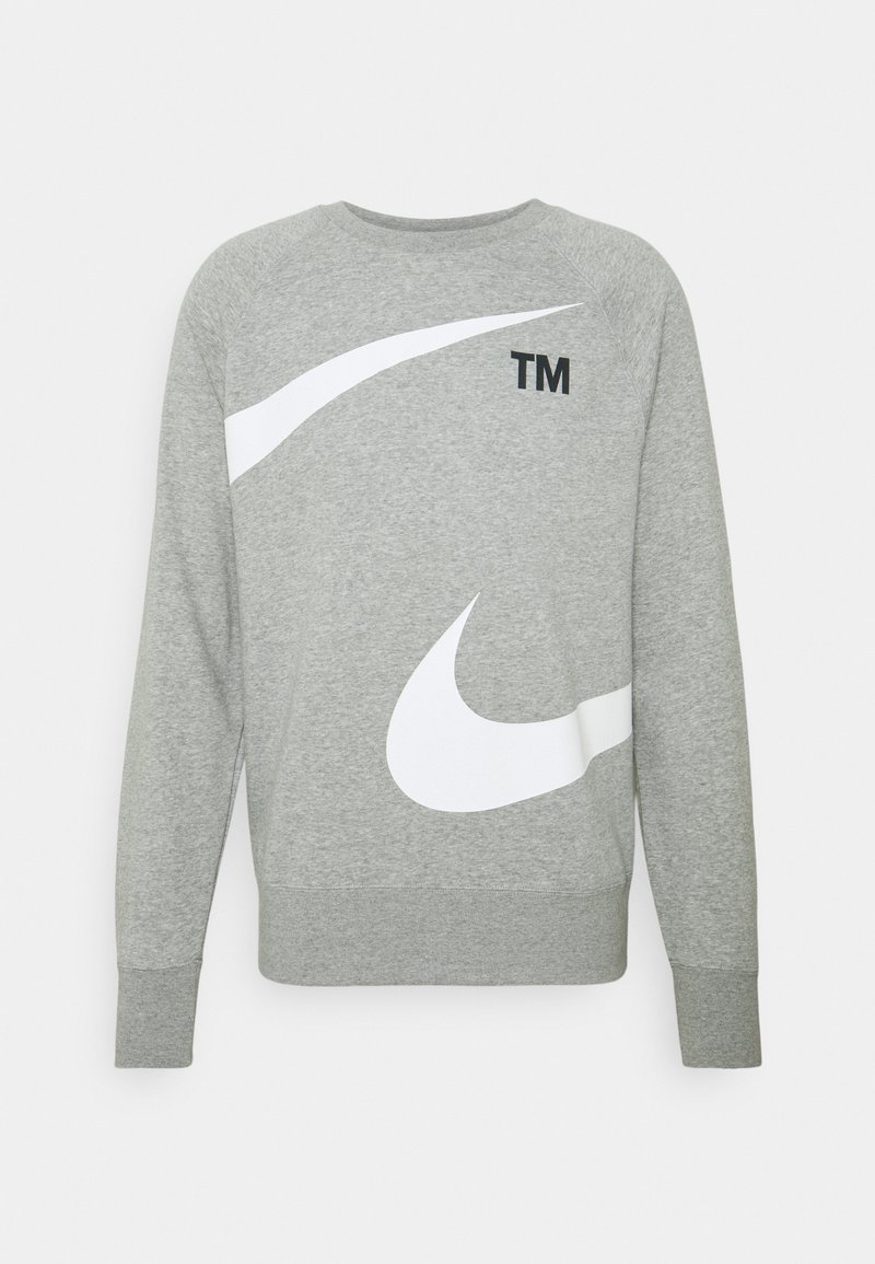 Grå sweatshirt med långa ärmar, med stora vita och svarta Nike-swoosh-designs och en liten "TM"-logotyp nära halsen. Mjukt material.