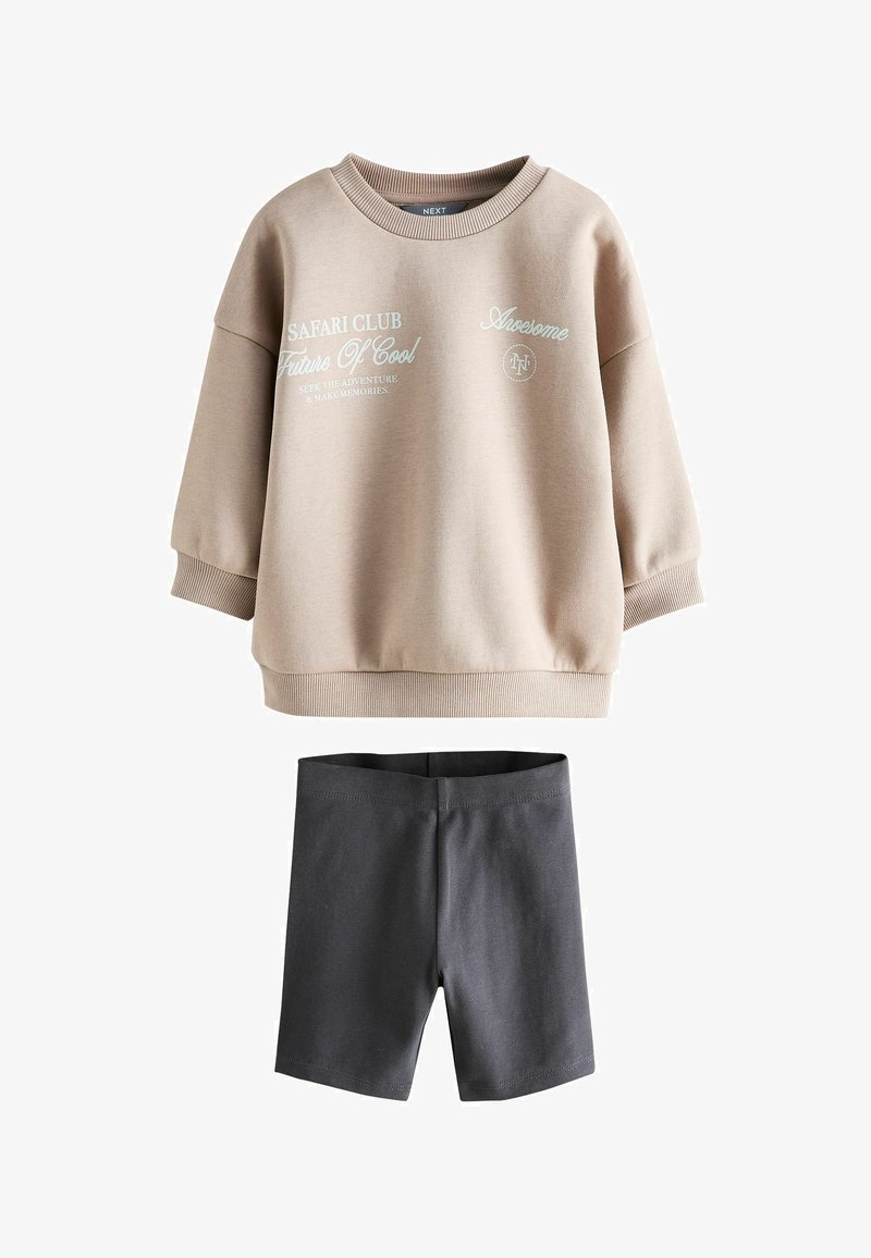 Ensemble pour enfants comprenant un sweat-shirt beige à manches longues avec texte imprimé et un short gris foncé jusqu'aux genoux.