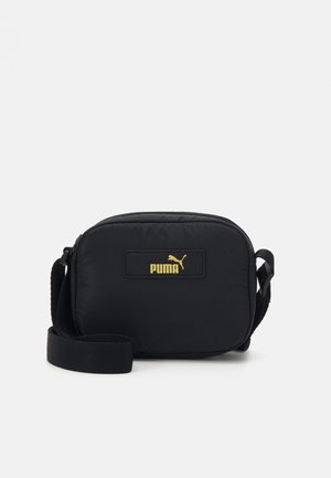 Borsa a tracolla nera in nylon di forma rettangolare, con un logo Puma giallo su una toppa nera e una tracolla regolabile.