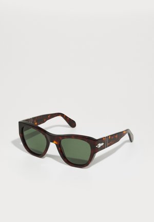 Schildpatt-Sonnenbrille mit grünen Gläsern, quadratischer Form und silbernem Akzent an den Bügeln. Glatte Textur mit stabilen Scharnieren.