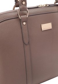 Taupe gestructureerde leren handtas met dubbele handvatten, goudkleurige accenten en een klein rechthoekig merkteken met de tekst "Paul Costelloe."