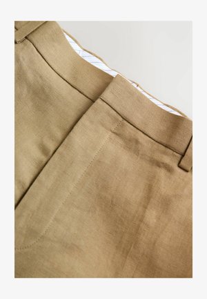 Pantaloni in lino marrone chiaro con una texture liscia, dotati di un frontale piatto, cintura e dettagli di cucitura discreti. La fodera interna presenta sottili righe.