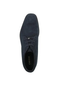 Zapato de ante azul marino con cordones y punta redonda, que presenta un brillo sutil, costuras contrastantes y una plantilla transpirable etiquetada como "GEOX RESPIRA."
