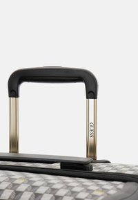 Black plastic telescopic handle with gold metal frame, attached to a textured gray suitcase featuring subtle diamond patterns and yellow accents.