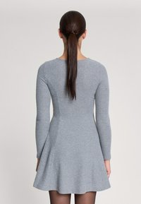 Abito a maglione grigio a coste con maniche lunghe, corpino aderente e gonna a ruota; texture liscia con scollatura rotonda e lunghezza a metà coscia.