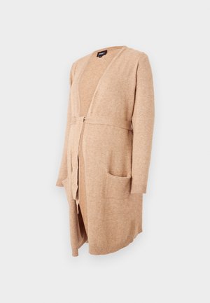 Cardigan beige en matière tricot douce. Design à l'avant ouvert avec une fermeture à nouer, deux poches plaquées et des poignets côtelés aux manches.