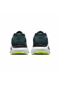 Scarpe da corsa Nike con tomaia verde scuro, dettagli neri e suola bianca con particolari verde neon. La vista posteriore mette in evidenza il design testurizzato.