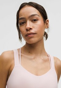 Jasnoróżowy kostium kąpielowy z cienkimi ramiączkami i dekoltem w kształcie litery V. Gładka tekstura z minimalną ilością elementów metalowych. Czyste linie i dopasowany krój.