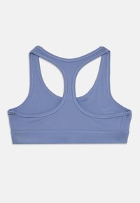 Sostén deportivo de tirantes en color lavanda con espalda tipo racerback, con tirantes anchos y el logo de Nike en la parte posterior, diseñado para actividades atléticas.