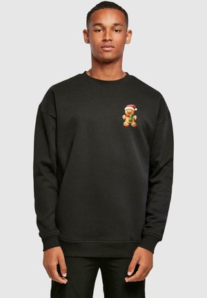 Black sweatshirt with a crew neck, featuring a gingerbread character wearing a Santa hat and holding a gift on the chest.