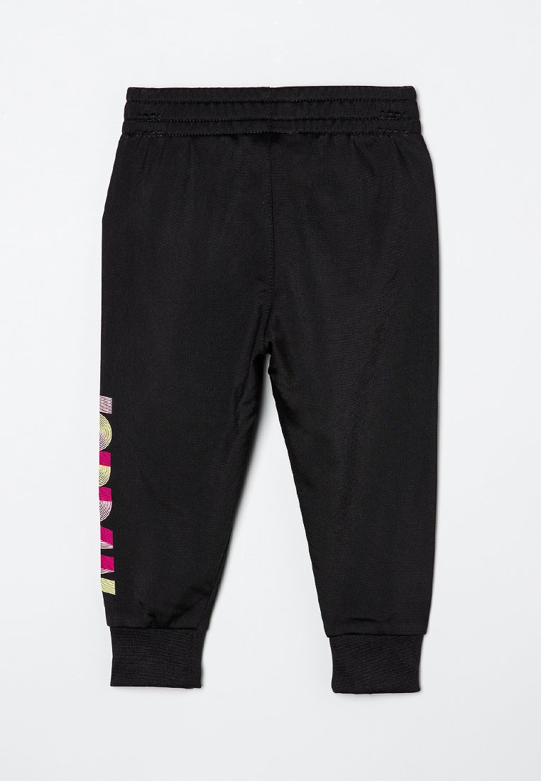 Pantalon de jogging noir en tissu lisse avec des poignets aux chevilles. Présente un design graphique coloré sur le côté gauche. Taille élastique.