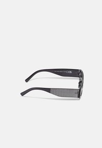 Ochelari de soare negri cu un model texturat, în carouri, pe braț. Hinge consolidate și lentile întunecate completează designul.
