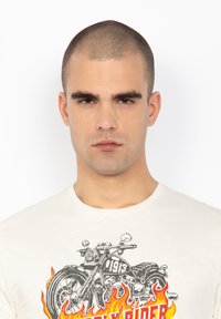 Witte katoenen T-shirt met een afbeelding van een motorfiets met vlammen en de tekst "Rider 1913," ronde halslijn en korte mouwen.