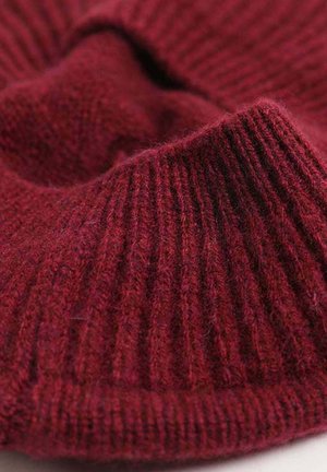 Strickstoff aus burgunderroter Wolle mit gerippter Textur und einer weichen, dicken Beschaffenheit, mit einem umgeschlagenen Rand für zusätzlichen Detail.