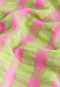 Tissu avec une texture froissée présentant un motif à carreaux aux carrés rose vif et vert clair.