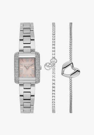 Reloj de metal plateado con esfera rectangular, dial rosa y acentos de cristal; incluye dos pulseras plateadas, una con un charm de corazón y otra con piedras claras.