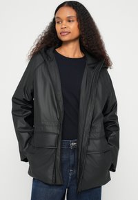 Μαύρο αδιάβροχο μπουφάν με κουκούλα, με φερμουάρ μπροστά, δύο μπροστινές τσέπες και λείο, υφασμάτινο φινίρισμα. Καθημερινό σχέδιο.