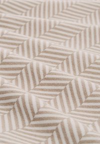 Gequilte stof met een visgraatpatroon in beige en crème strepen, met een zachte textuur en een gelaagde uitstraling.