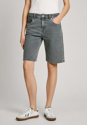 Jeansshorts i mörkgrått med en klassisk passform, som har framfickor och sydda fållar. Kombinerat med vita sneakers.