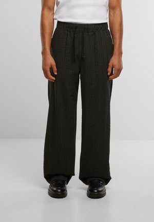 Schwarze, weite Hosen aus strukturiertem Stoff mit einem gemusterten Finish. Verfügt über einen elastischen Bund und einen lockeren Schnitt.