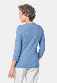 Hellblauer Pullover mit Rautenmuster, Dreiviertelärmeln, geripptem Ausschnitt und Saum sowie glatter Textur.