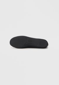 Zwarte schoenzool met een gestructureerd grippatroon, ronde neus en een gladde rand. Gemaakt van flexibel materiaal, ontworpen voor comfort en duurzaamheid.