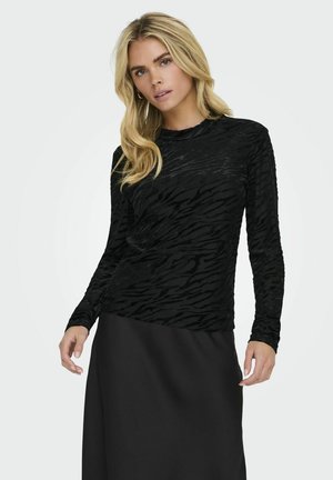 Black long-sleeve top with a textured zebra pattern. Fitted design with a round neckline, paired with a solid black skirt.